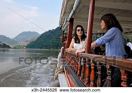 young women standing at the railing of a cruise boat, owned by ´´ The Luang Say Lodge & Cruises´´, on Mekong River, between Pakbeng and Luang Prabang, Oudomxay Province, Laos, Southeast Asia. View Large Photo Image Stock Photograph - young women standing at the railing of a cruise boat, owned by ´´ The Luang Say Lodge & Cruises´´, on Mekong River, between Pakbeng and Luang Prabang, Oudomxay Province, Laos, Southeast Asia.. Fotosearch