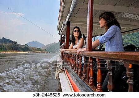 young women standing at the railing of a cruise boat, owned by ´´ The Luang Say Lodge & Cruises´´, on Mekong River, between Pakbeng and Luang Prabang, Oudomxay Province, Laos, Southeast Asia. View Large Photo Image Stock Photography - young women standing at the railing of a cruise boat, owned by ´´ The Luang Say Lodge & Cruises´´, on Mekong River, between Pakbeng and Luang Prabang, Oudomxay Province, Laos, Southeast Asia.. Fotosearch