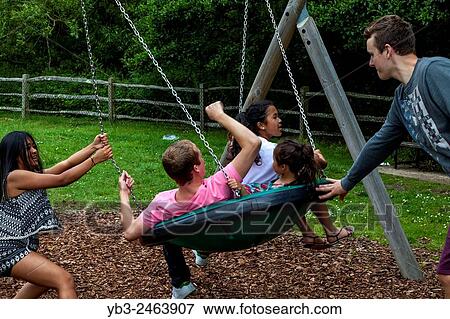 A Family Playing On The Swings, Play Area, Sussex, UK. View Large Photo Image Stock Photo - A Family Playing On The Swings, Play Area, Sussex, UK.. Fotosearch