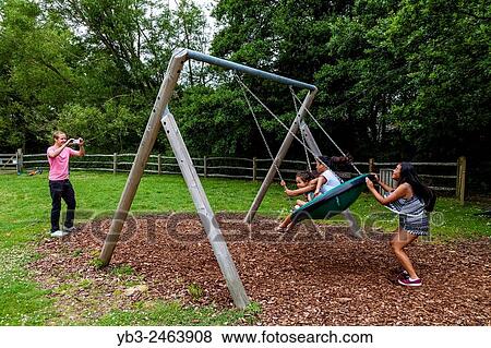 A Family Playing On The Swings, Play Area, Sussex, UK. View Large Photo Image Stock Photo - A Family Playing On The Swings, Play Area, Sussex, UK.. Fotosearch