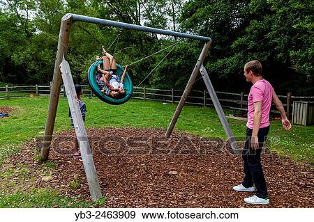 A Family Playing On The Swings, Play Area, Sussex, UK. View Large Photo Image Stock Photo - A Family Playing On The Swings, Play Area, Sussex, UK.. Fotosearch