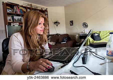 Amsterdam, Netherlands. Columbian female immigrant working behind her laptop computer on her dining room table. View Large Photo Image Stock Photograph - Amsterdam, Netherlands. Columbian female immigrant working behind her laptop computer on her dining room table.. Fotosearch
