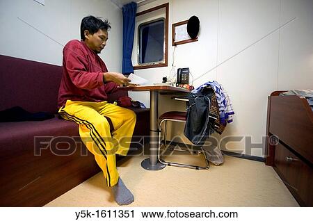 An Indonesian seaman or sailor on the container-vessel MV Flintercape, during a journey from Rotterdam, Netherlands, to Sundsvall, Sweden. The man is an ´Able Seaman´, who generally works on deck, and now prepares for the night in his cabin. View Large Photo Image Stock Image - An Indonesian seaman or sailor on the container-vessel MV Flintercape, during a journey from Rotterdam, Netherlands, to Sundsvall, Sweden. The man is an ´Able Seaman´, who generally works on deck, and now prepares for the night in his cabin.. Fotosearch
