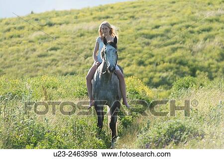 Stock Photo - Barefoot girl riding a grey horse.. Fotosearch