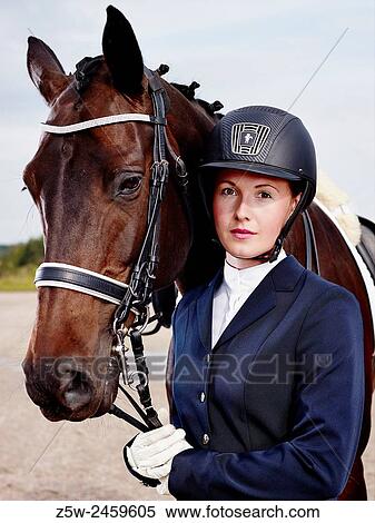 Stock Photography - Brown horse and beautiful woman wearing horse riding apparel.. Fotosearch