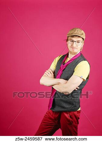 Stock Photo - Expressive hipster wearing a vest and pink tie, pink background and studio shot.. Fotosearch