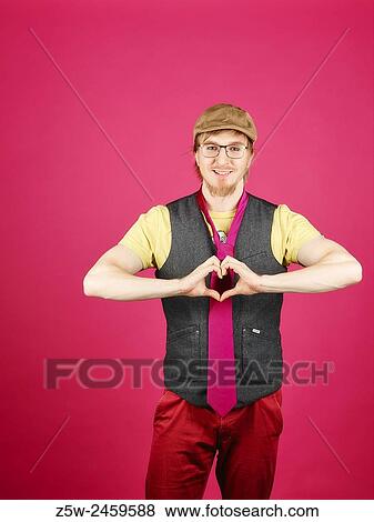 Stock Photo - Expressive hipster wearing a vest and pink tie, pink background and studio shot.. Fotosearch