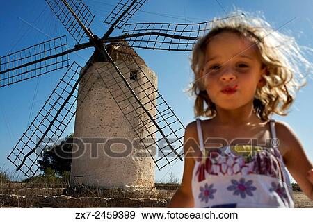 Stock Photo - Funy girl in the windmill, Formentera, Balearic Islands, Spain. Old Windmill in el Pilar de la Mola on the island Formentera, Balearic Islands, Spain.. Fotosearch