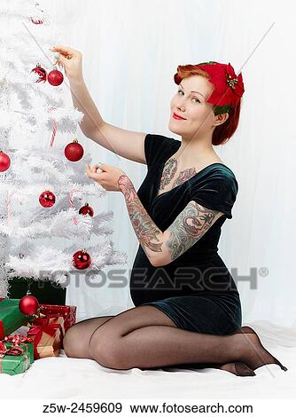 Stock Photo - Happy pregnant woman decorates the christmas tree.. Fotosearch
