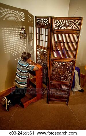 Hidden by a screen, a priest hears confession from a kneeling boy parishioner at a Laguna Niguel, CA, Catholic church. MODEL RELEASE. View Large Photo Image Stock Image - Hidden by a screen, a priest hears confession from a kneeling boy parishioner at a Laguna Niguel, CA, Catholic church. MODEL RELEASE.. Fotosearch