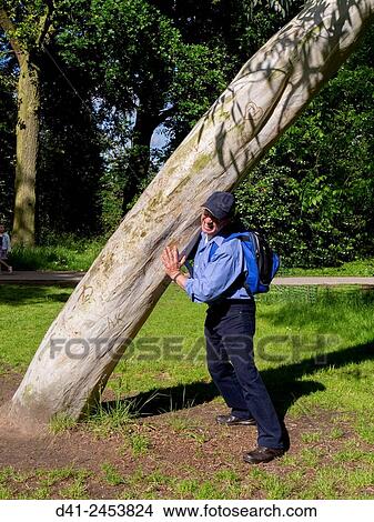man holds up leaning tree. View Large Photo Image Picture - man holds up leaning tree.. Fotosearch