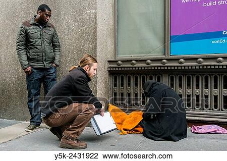 Stock Image - New York, USA, Male social workers with Goddard Riverside, reaching out to a homeless person, living in the streets of Manhattan.. Fotosearch