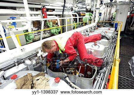 Stock Photo - Port of Rotterdam, Rotterdam, Netherlands. Engineer maintaining the engine of his sea going vessel.. Fotosearch