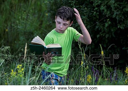 Picture - Russia. Belgorod region. Solomino village. The boy in the meadow with a book.. Fotosearch