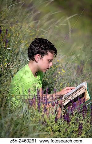 Stock Image - Russia. Belgorod region. Solomino village. The boy in the meadow with a book.. Fotosearch