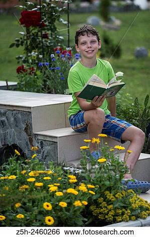 Stock Photograph - Russia. Belgorod region. Solomino village. The boy in the meadow with a book.. Fotosearch