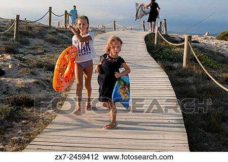 Stock Image - Sa Roqueta Beach and Ses Illetes Beach, Balearic Islands, Formentera, Spain. Funy girls with floats.. Fotosearch