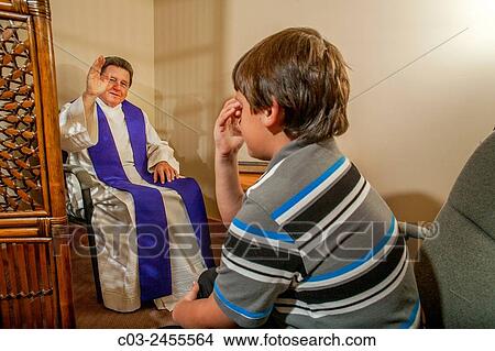Picture - Sitting face to face, a priest gives absolution after hearing the confession of a boy parishioner at a Laguna Niguel, CA, Catholic church. Note vestments. MODEL RELEASE.. Fotosearch