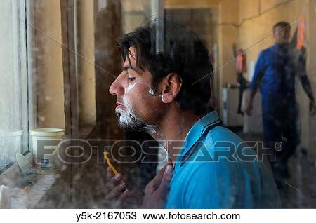 Stock Image - Sofia, Bulgaria. Male, Syrian refugee in refugee camp Voenna Rampa shaving in front of an open window.. Fotosearch