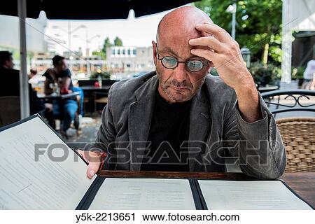 Tilburg, Netherlands. Bald, be glassed and middle-aged man, studying on a restaurant´s menu, before ordering diner. View Large Photo Image Stock Image - Tilburg, Netherlands. Bald, be glassed and middle-aged man, studying on a restaurant´s menu, before ordering diner.. Fotosearch