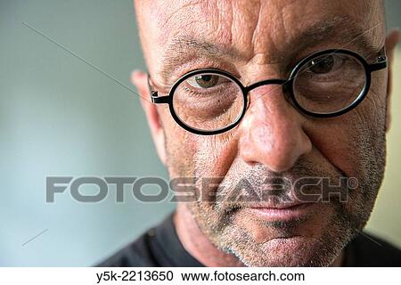 Stock Image - Tilburg, Netherlands. Studio-portrait of a bald, be glassed and middle-aged man, talking, speaking and telling a story.. Fotosearch