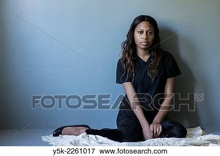 Tilburg, Netherlands. Studio shot of dark skinned woman from African decent sitting on a blanked against a grey, concrete wall. View Large Photo Image Stock Photo - Tilburg, Netherlands. Studio shot of dark skinned woman from African decent sitting on a blanked against a grey, concrete wall.. Fotosearch