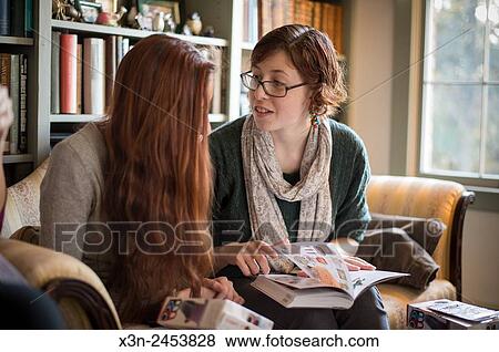 Two young women sitting on couch in living room in Fallston, Maryland, USA. View Large Photo Image Stock Photo - Two young women sitting on couch in living room in Fallston, Maryland, USA.. Fotosearch
