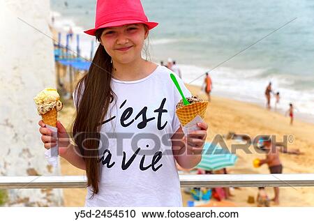 young girl with ice-cream in both hands, in the background beach in Armacao de Pera, Silves, Algarve, Portugal, Europe. View Large Photo Image Stock Image - young girl with ice-cream in both hands, in the background beach in Armacao de Pera, Silves, Algarve, Portugal, Europe.. Fotosearch
