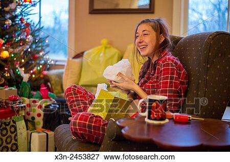 Young woman opening Christmas present wearing plaid pajamas in Fallston, Maryland, USA. View Large Photo Image Stock Photo - Young woman opening Christmas present wearing plaid pajamas in Fallston, Maryland, USA.. Fotosearch