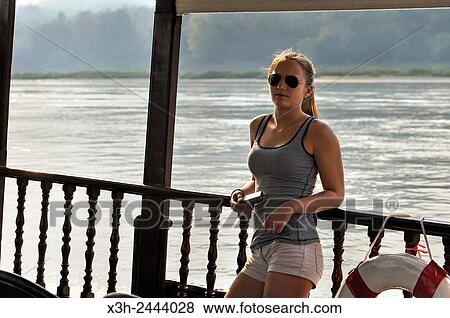 Stock Photo - young woman standing at the railing of a cruise boat, owned by Â´Â´ The Luang Say Lodge & CruisesÂ´Â´, on Mekong River, between Pakbeng and Luang Prabang, Oudomxay Province, Laos, Southeast Asia.. Fotosearch