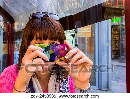 Young woman taking a photograph with her mobile phone while facing the camera. Shooting Date 14/04/2015 View Large Photo Image Stock Photography - Young woman taking a photograph with her mobile phone while facing the camera. Shooting Date 14/04/2015. Fotosearch