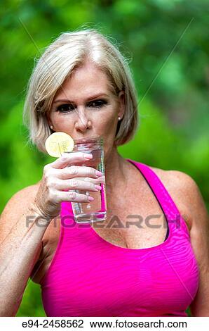 56 year old blond woman drinking from a glass of water, outdoors. View Large Photo Image Stock Image - 56 year old blond woman drinking from a glass of water, outdoors.. Fotosearch