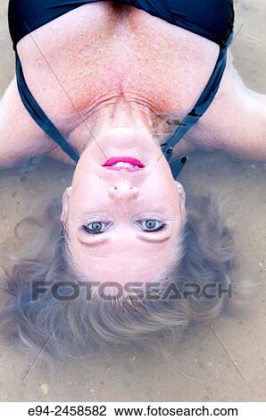 56 year old blond woman in a swim suit in shallow water looking up at the camera. View Large Photo Image Stock Image - 56 year old blond woman in a swim suit in shallow water looking up at the camera.. Fotosearch