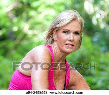 Stock Image - 56 year old blond woman smiling at the camera, outdoors.. Fotosearch