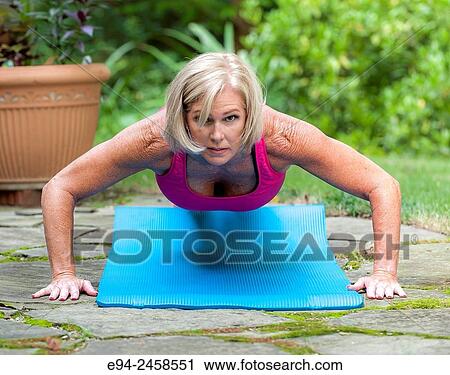 A 56 year old blond woman doing a push up on a yoga mat, outdoors. View Large Photo Image Stock Image - A 56 year old blond woman doing a push up on a yoga mat, outdoors.. Fotosearch