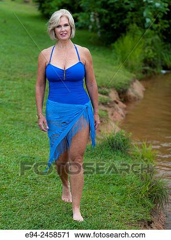 A 56 year old blond woman wearing a swim suit walking on grass, outdoors. View Large Photo Image Stock Image - A 56 year old blond woman wearing a swim suit walking on grass, outdoors.. Fotosearch