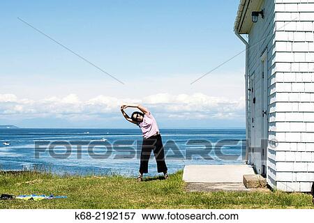 Stock Photo - a middle-aged woman exercises outdoors at East Point, Saturna Island, Gulf Islands, British Columbia, Canada.. Fotosearch