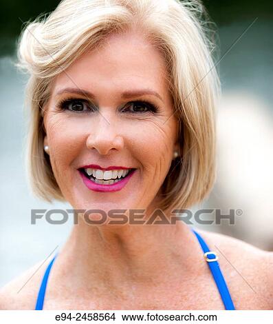 A portrait of a 56 year old blond woman smiling directly at the camera, outdoors. View Large Photo Image Picture - A portrait of a 56 year old blond woman smiling directly at the camera, outdoors.. Fotosearch