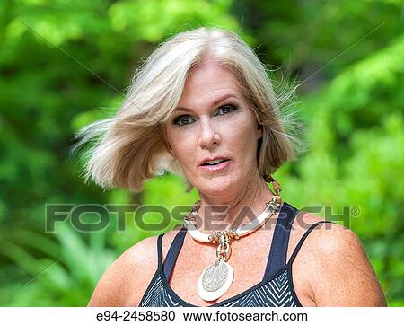 A portrait of a 56 year old blond woman looking directly at the camera, outdoors.. View Large Photo Image Stock Image - A portrait of a 56 year old blond woman looking directly at the camera, outdoors... Fotosearch