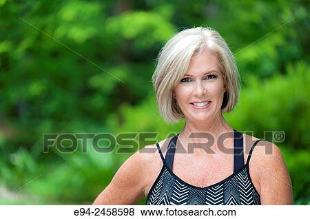 A portrait of a 56 year old blond woman smiling directly at the camera, outdoors. View Large Photo Image Stock Photo - A portrait of a 56 year old blond woman smiling directly at the camera, outdoors.. Fotosearch