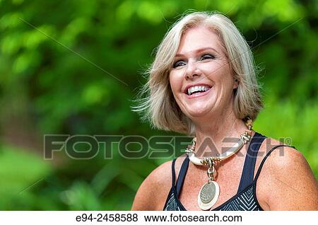 A portrait of a smiling 56 year old blond woman looking away from the camera, outdoors. View Large Photo Image Stock Photo - A portrait of a smiling 56 year old blond woman looking away from the camera, outdoors.. Fotosearch