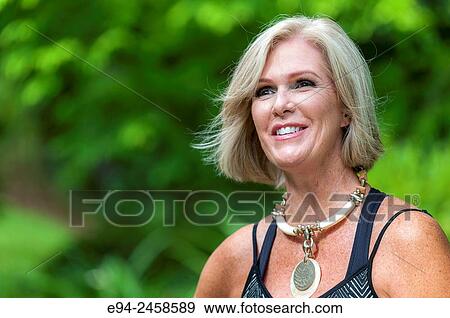 A portrait of a smiling 56 year old blond woman looking away from the camera, outdoors. View Large Photo Image Stock Photo - A portrait of a smiling 56 year old blond woman looking away from the camera, outdoors.. Fotosearch