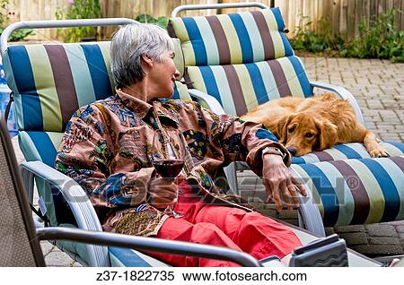 Stock Photography - A woman relaxes with a dog on the deck in her backyard, Ontario, Canada. Fotosearch