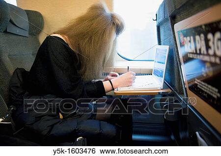A young, female Swedish student traveling by train from Sundsvall to Stockholm. She is using her laptop computer during the trip and she is just filling out the model release with a pen. View Large Photo Image Stock Photograph - A young, female Swedish student traveling by train from Sundsvall to Stockholm. She is using her laptop computer during the trip and she is just filling out the model release with a pen.. Fotosearch