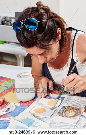 Stock Photograph - An amateur artist apply raku glaze on ceramic object.. Fotosearch