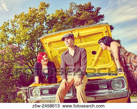 Stock Image - Friends together and old Dodge - 70's theme, intentional film grain added.. Fotosearch