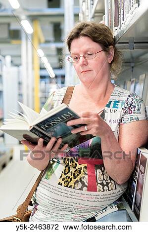 Gouda, Netherlands. Middle aged woman choosing a book to read from the library shelves. View Large Photo Image Stock Image - Gouda, Netherlands. Middle aged woman choosing a book to read from the library shelves.. Fotosearch