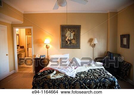 Hotel room with an unmade bed with bathroom in background. View Large Photo Image Picture - Hotel room with an unmade bed with bathroom in background.. Fotosearch