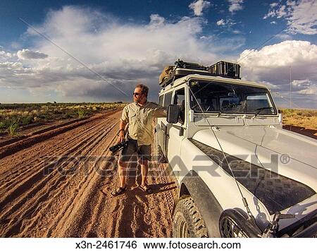 Namibia - Photographer looking out in the distance on a dirt road in Africa at dusk. View Large Photo Image Stock Photograph - Namibia - Photographer looking out in the distance on a dirt road in Africa at dusk.. Fotosearch