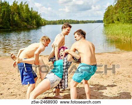 Stock Image - The group of the friends chilling out on the beach, summer day. Shot in southern Finland.. Fotosearch